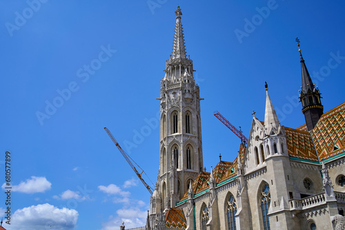 Close ups of the decorative roof and main tower of the 13th-century church Matthias Church with cranes in background in Budapest, Hungary.