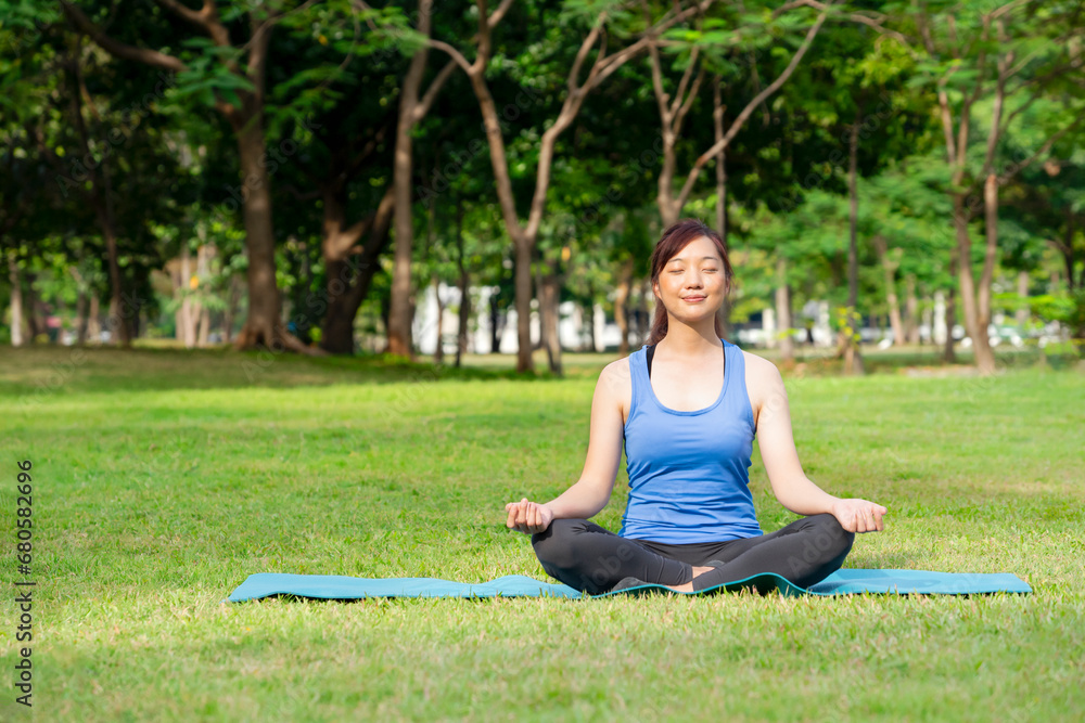 A pleasure woman closed eyes sitting on yoga matt doing yoga in the nature park among the morning sunshine A pleasure woman closed eyes sitting on yoga matt doing yoga in the nature park among the morning sunshine