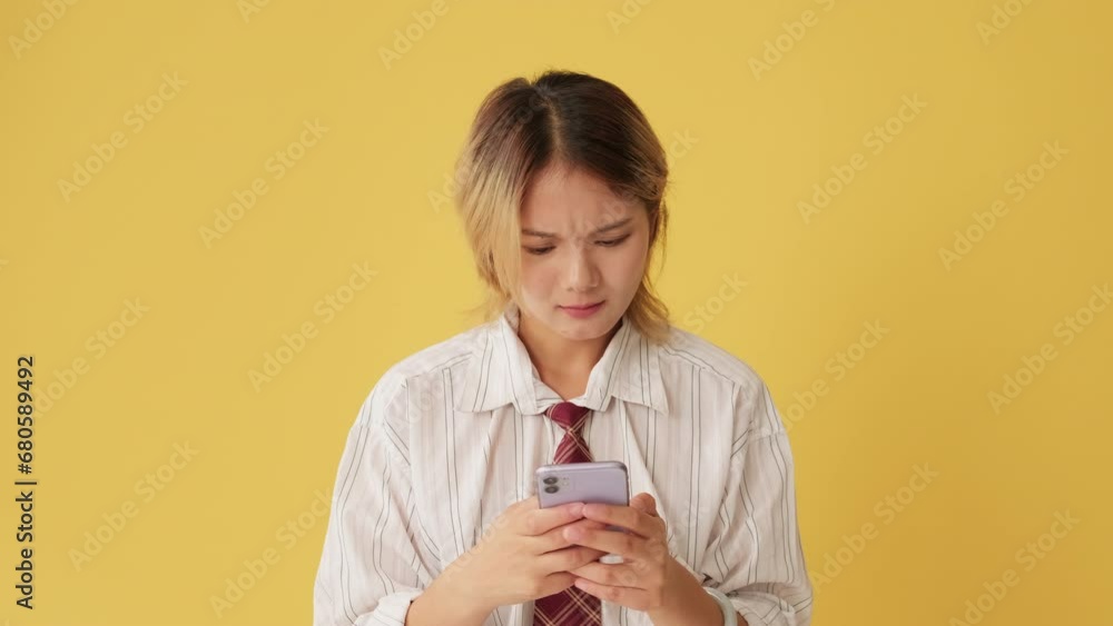 Upset woman using mobile phone, receiving bad news isolated on yellow background in studio Upset woman using mobile phone, receiving bad news isolated on yellow background in studio