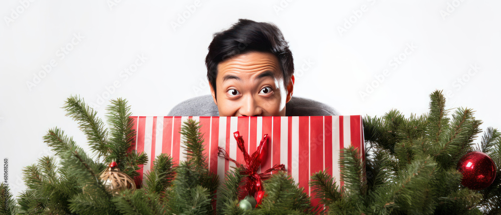 Joyful man in a red hat peeking from a Christmas tree.