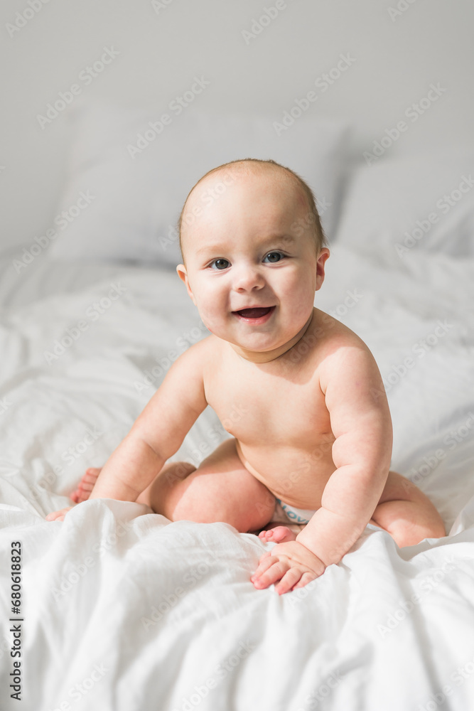 Smiling newborn baby on a white bed at home, the concept of a happy healthy infant baby. Generation alpha and gen alpha Smiling newborn baby on a white bed at home, the concept of a happy healthy infant baby. Generation alpha and gen alpha