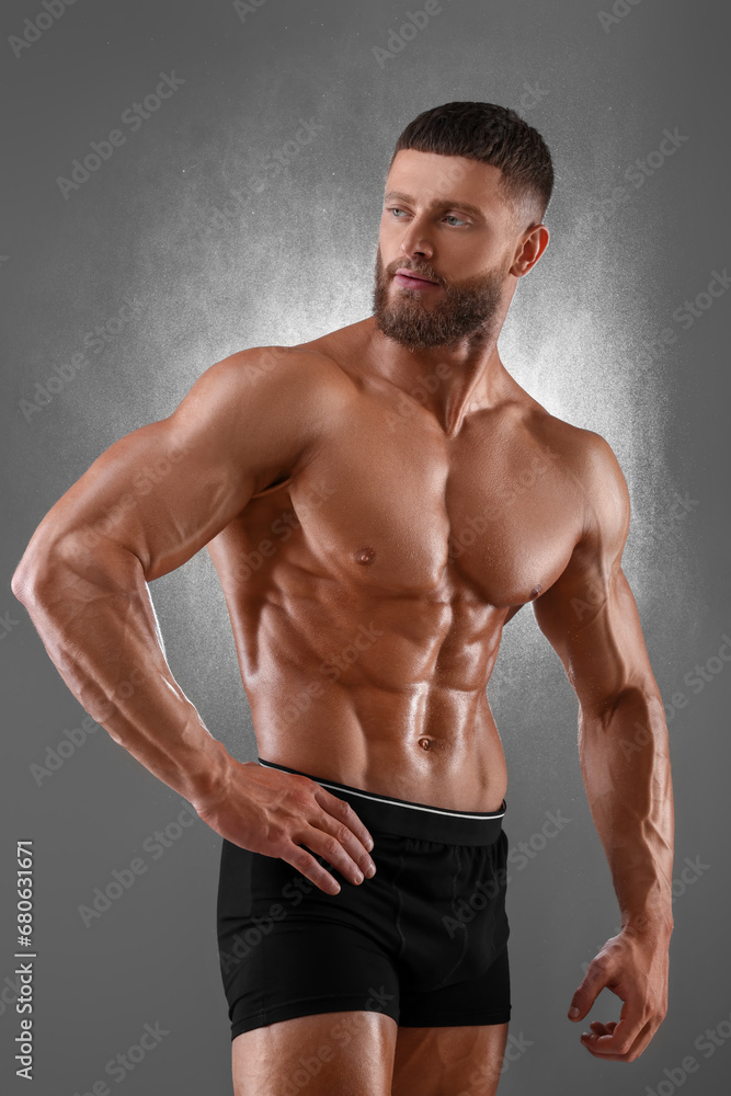 Young bodybuilder with muscular body on grey background