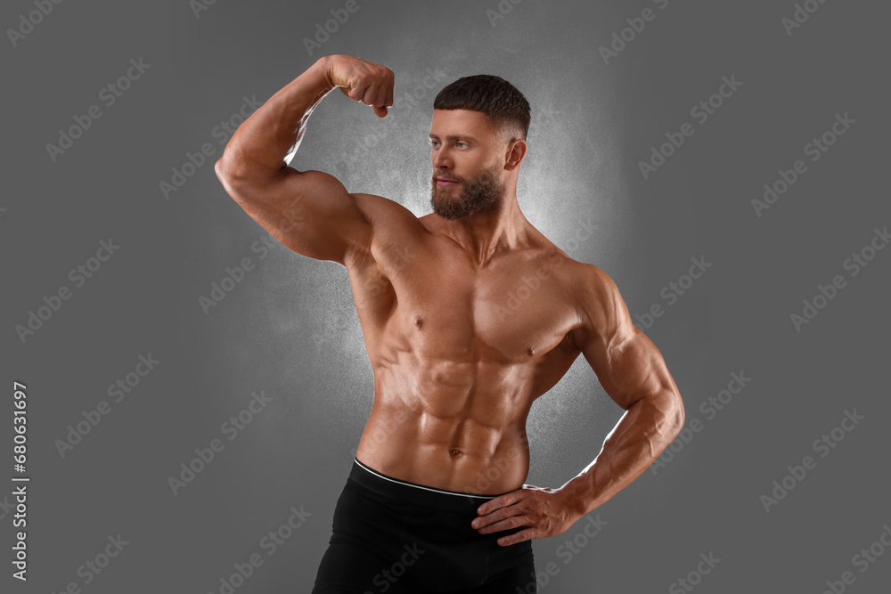 Young bodybuilder with muscular body on grey background