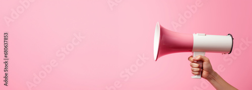 arm extended holding a pink megaphone against a pink backdrop