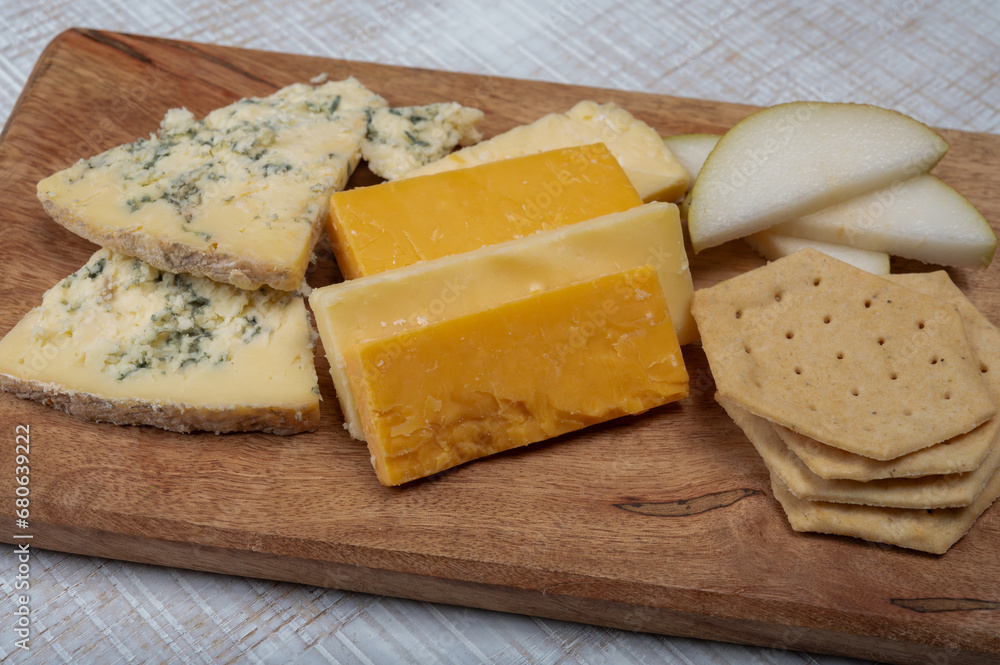 English cheeses collection, mature and coloured cheddar cheese and semi-soft, crumbly old stilton blue cheese close up