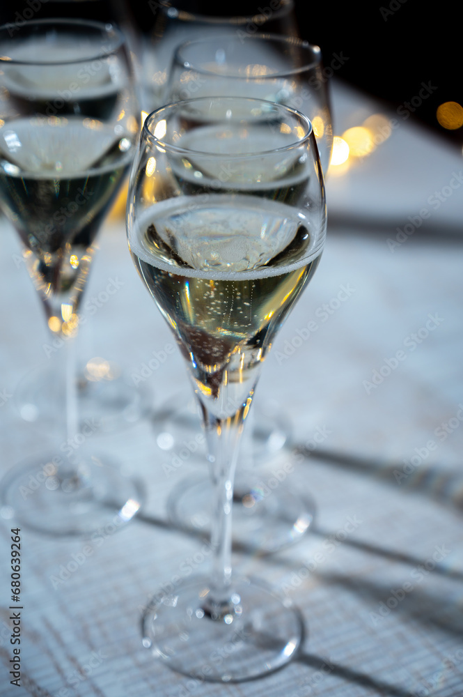 New year party, small bubbles of brut champagne cava or prosecco wine in tulip glasses with garland lights on background New year party, small bubbles of brut champagne cava or prosecco wine in tulip glasses with garland lights on background