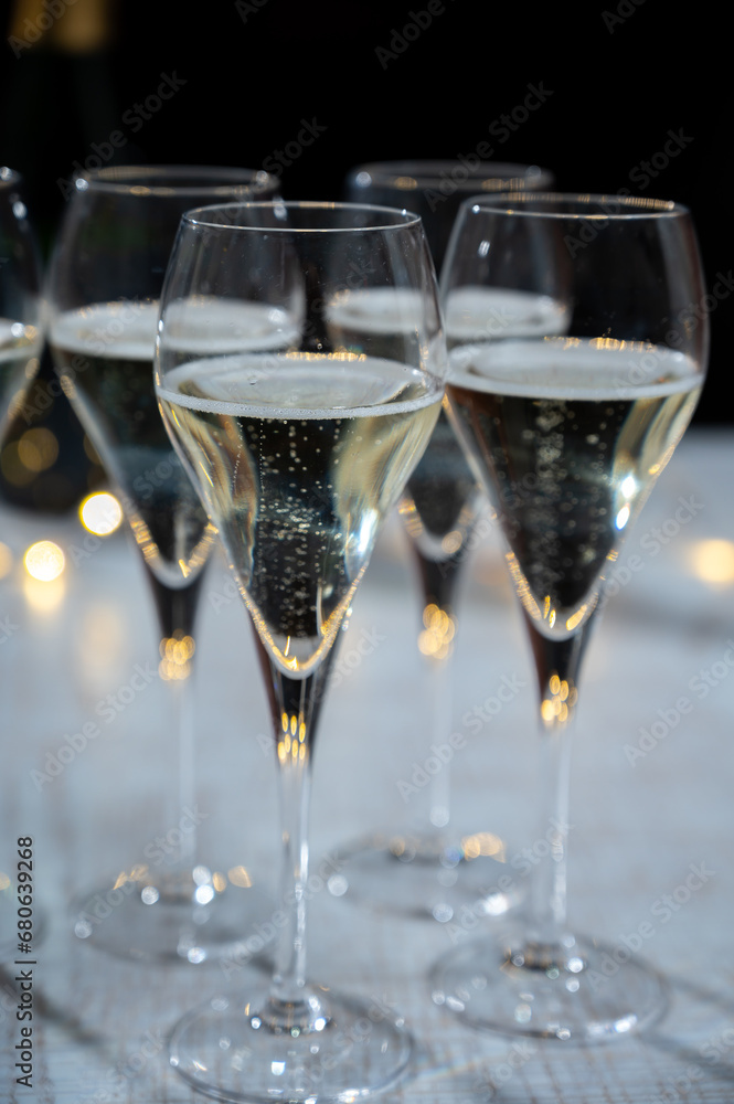New year party, small bubbles of brut champagne cava or prosecco wine in tulip glasses with garland lights on background New year party, small bubbles of brut champagne cava or prosecco wine in tulip glasses with garland lights on background
