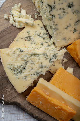 English cheeses collection, mature and coloured cheddar cheese and semi-soft, crumbly old stilton blue cheese close up