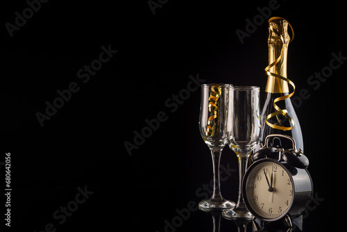 Alarm clock and champagne glasses on black background with copy space. New Year and Christmas celebration concept.