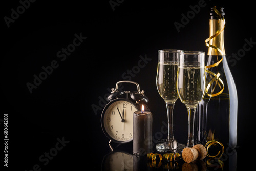Champagne flutes and alarm clock on black background with copy space, New Year and Christmas celebration concept.