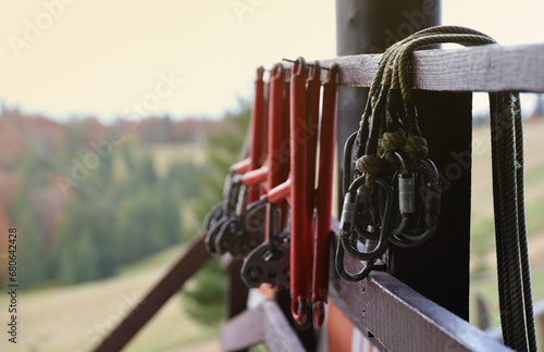 large metal locking carabiners with rope, climbing gear hanging on the store room. Height safety harness and arborist equipment close up