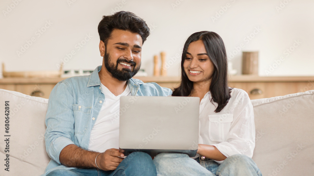 Fototapeta premium Happy indian couple smiling while looking at a laptop