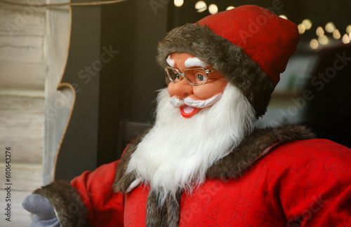Santa claus big plastic figure with classic santa clothes and hat close to wooden house © mehaniq41