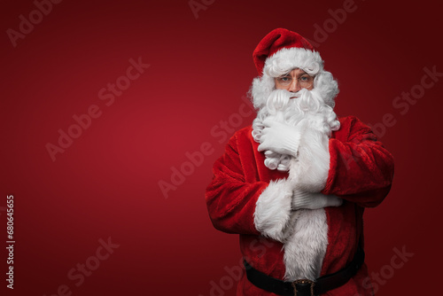 Shot of bearded santa with red winter costume looking at camera.