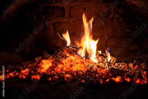 Logs of firewood burn out in the oven. Coals and flames in the fireplace.