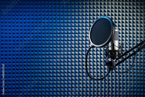 Professional microphone on the stand. Recording studio with acoustical wall panel.
