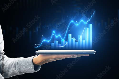 Hand holding tablet displaying growth charts and stock market trends photo
