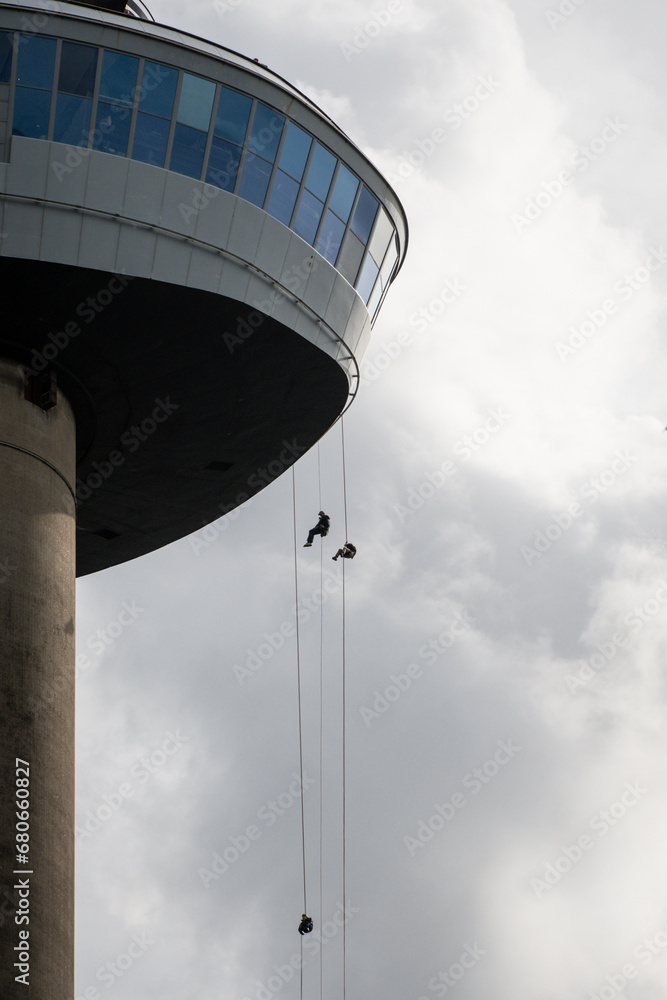 daring adrenaline junkies abseil from the Euromast tower in Rotterdam Netherlands to the ground. rappelling sport people in action over the edge