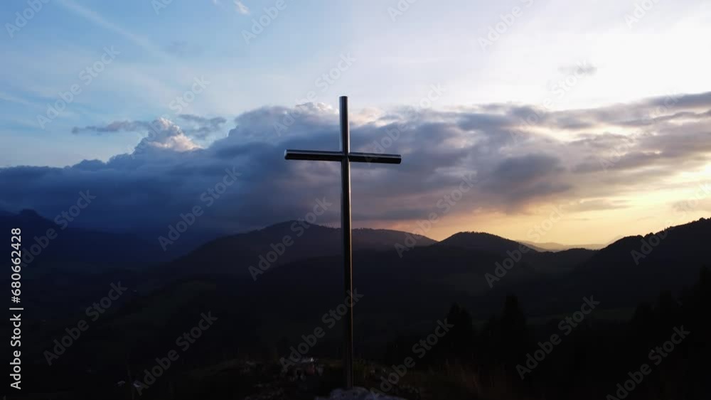 Aerial view of a religious Christian steel cross on a hill in the mountainous countryside, in sunset Aerial view of a religious Christian steel cross on a hill in the mountainous countryside, in sunset