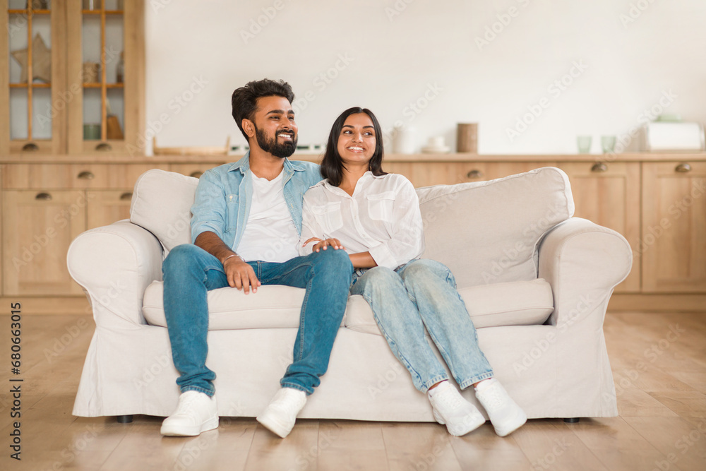 Content young indian couple sitting together on a sofa Content young indian couple sitting together on a sofa