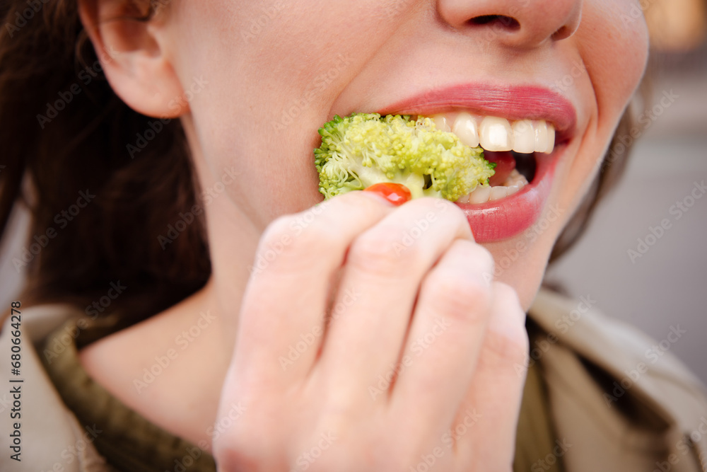 woman tastes healthy green broccoli for healthy lunch on street woman tastes healthy green broccoli for healthy lunch on street
