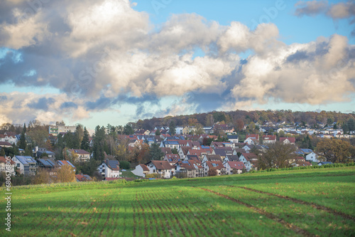 Panorama einer Ortschaft in ländlichem Umfeld mit dramatischem Wolkenhimmel.