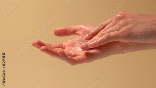 Woman applies cream on palm with finger and rubs it on beige isolated background. Body and face skin care concept, cosmetic texture photo