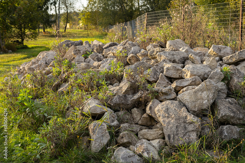 Large stones lie in a large pile on the grass. Beautiful large stones stacked in the grass. Rock stones are dumped into a large pile in the green grass.