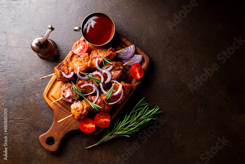 Pork kebab with barbecue sauce and tomatoes on a dark background, top view copy space for text