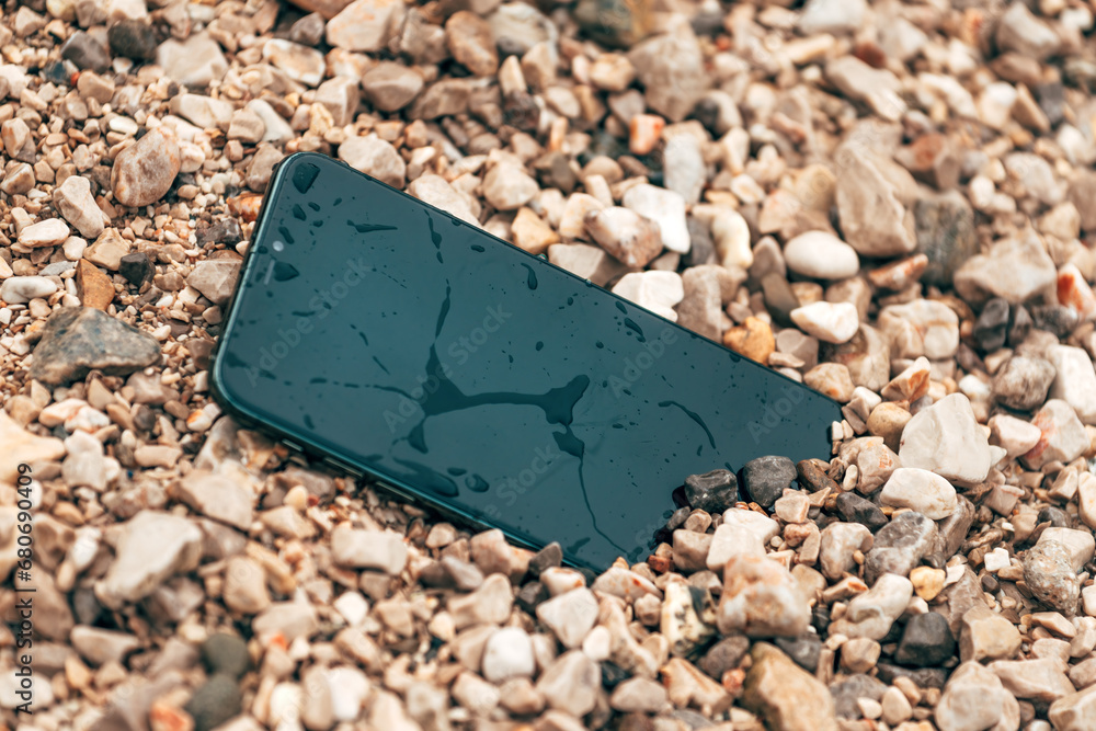 Wet and damaged smartphone in beach pebbles Wet and damaged smartphone in beach pebbles