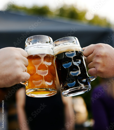 glasses with light and dark beer clink in men's hands
