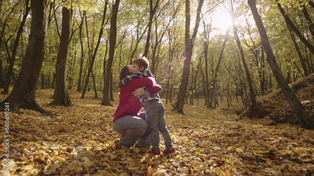 Beneath the Canopy of Fall: Mother and Son's Playful Leaf-Tossing Adventure in the Enchanting Park. High quality 4k footage Beneath the Canopy of Fall: Mother and Son's Playful Leaf-Tossing Adventure in the Enchanting Park. High quality 4k footage