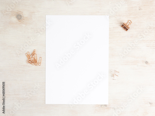 Paper A4 empty on wooden table with paperclips and pins. Office stationery mockup flat lay.