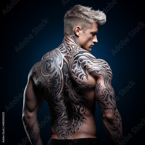 Young caucasian athletic man with abstract tattoo on a dark background