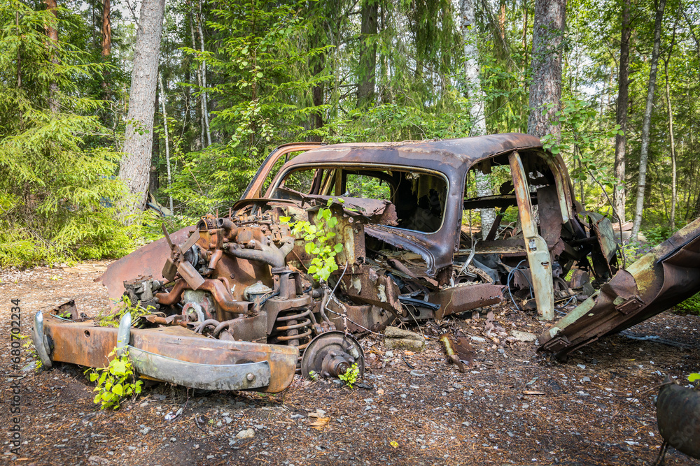 Old abandoned car wreck hidden in a forest, famous dark tourism destination in Sweden Old abandoned car wreck hidden in a forest, famous dark tourism destination in Sweden