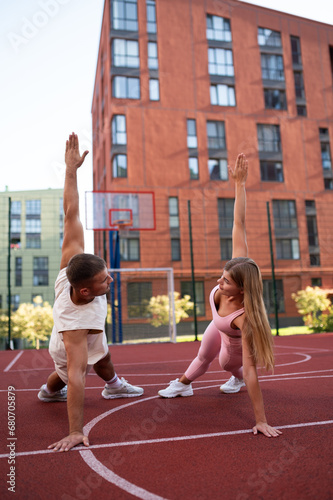 An active sports woman and her coach are doing exercises on the basketball court