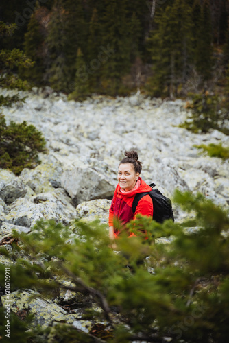 girl smiling standing in the mountains on the background of rocks, mountain tourist route, hiking in the forest.