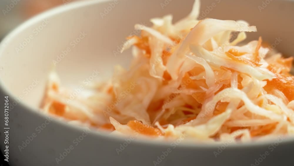 Eating fresh sour fermented sauerkraut with a fork from a kitchen bowl with chopped white cabbage and red carrot close up. Healthy food Eating fresh sour fermented sauerkraut with a fork from a kitchen bowl with chopped white cabbage and red carrot close up. Healthy food