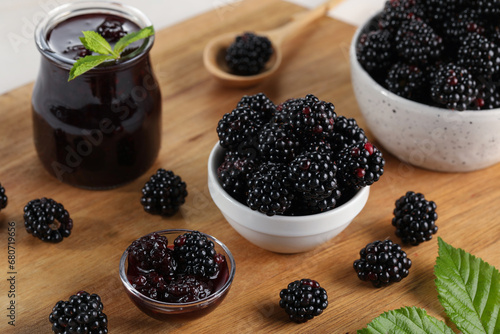 Tasty blackberry jam and fresh berries on wooden board, closeup