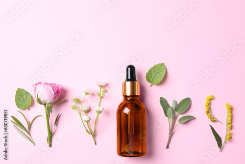 Bottle of essential oil, different herbs and flowers on pink background, flat lay. Space for text