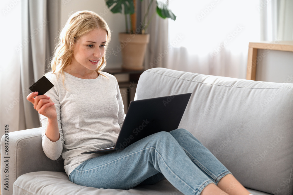 Woman holding plastic credit card, using laptop, pay bills online Woman holding plastic credit card, using laptop, pay bills online