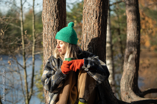Foto Tired female sitting on river brink leaning against pine tree, resting after hik