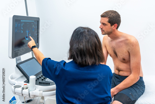 Patient sitting on stretcher while cardiologist performing a echocardiogram test in the hospital