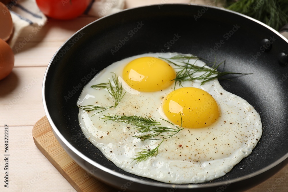 Frying pan with tasty cooked eggs, dill and other products on light wooden table, closeup Frying pan with tasty cooked eggs, dill and other products on light wooden table, closeup