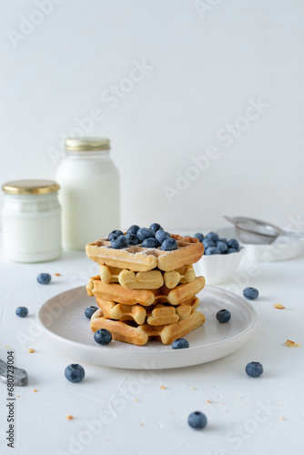 Belgian waffles with blueberries and honey on a white background. Serving breakfast with homemade cakes.