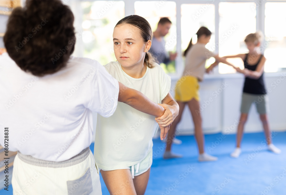 Pupils train to perform defense by jowl thrust opponent, while learning self-defense techniques. Child practices basic technique expedient during classes with teacher in krav maga class