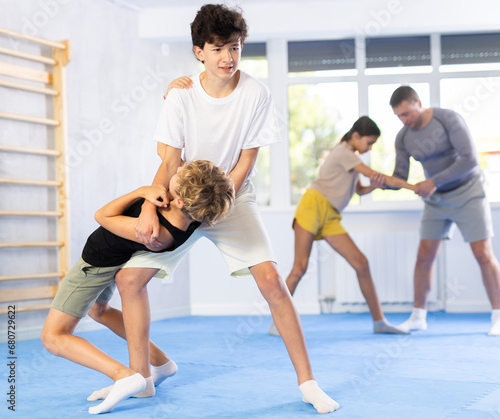 Two preteen boys doing a head kick during self-defense training
