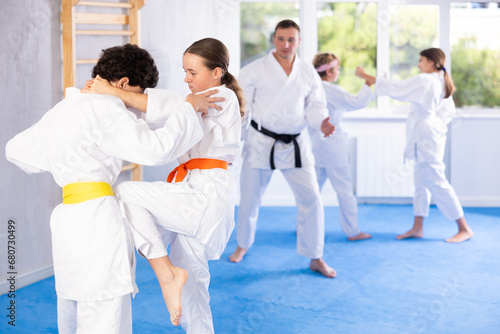 Girl and boy in kimono sparring together in gym during karate training