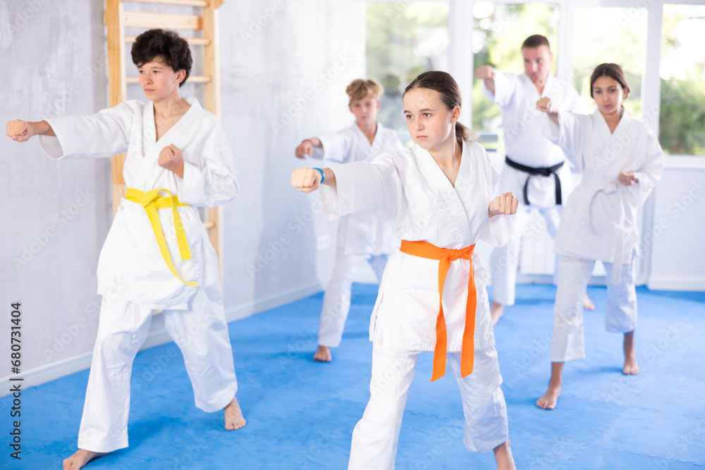 Kata karate teacher conducts classes and performs movements and fighting techniques together with boys and girls students to prepare them for competitions.