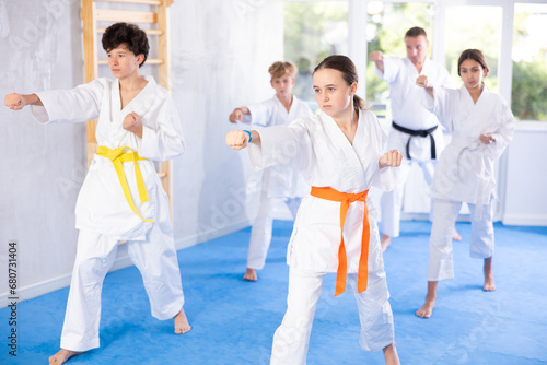 Kata karate teacher conducts classes and performs movements and fighting techniques together with boys and girls students to prepare them for competitions.